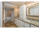 Bathroom with granite counters, white cabinets, double sinks, and a stone backsplash accent wall at 3241 Brushwood Ct, Clearwater, FL 33761
