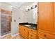 Bathroom featuring wood cabinets, black granite counters, walk-in shower with decorative tile and black fixtures at 3505 Seaway Dr, New Port Richey, FL 34652