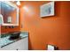 Powder room with vessel sink on granite countertop, orange wall, and decorative wall art at 3505 Seaway Dr, New Port Richey, FL 34652