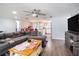 Open-concept living room with gray sectional, ceiling fan, and view into dining area and kitchen at 512 Red Mangrove Ln, Apollo Beach, FL 33572