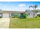 A well maintained single story home with a paved driveway, mature trees, and fresh landscaping on a sunny day at 5519 Homewood Dr, Sarasota, FL 34232