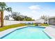 Sparkling turquoise pool with a white tile trim, green grass, white vinyl fence, hot tub and blue chairs in the background at 5519 Homewood Dr, Sarasota, FL 34232