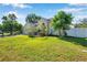 Bright green lawn in front of this home with trees, shrubs, and a white fence on the property line at 6130 Japonica Ct, New Port Richey, FL 34655