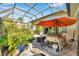 Enclosed patio space with screen enclosure and an outdoor grill under an umbrella at 6130 Japonica Ct, New Port Richey, FL 34655