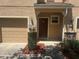 Welcoming townhouse entrance featuring a brown door, small shrubbery, and a tan colored garage door at 778 Spring Flowers Trl, Brandon, FL 33511