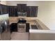 Modern kitchen with stainless steel appliances, dark cabinets, and granite countertops at 778 Spring Flowers Trl, Brandon, FL 33511