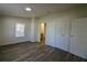 Bedroom featuring neutral walls, gray wood-look flooring, window with blinds, and a view of the attached bathroom at 9161 Codel Loop, New Port Richey, FL 34654