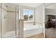 Bright bathroom featuring a shower, soaking tub beneath a window, and beige tiled flooring at 11118 Running Pine Dr, Riverview, FL 33569