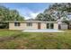 Tan single-story home with a brown door, sliding glass door, and a gray storage shed on a grassy lot at 1205 E Hamilton Ave, Tampa, FL 33604