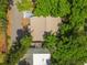 Birds eye view of home with a brown roof surrounded by lush greenery and a nearby street at 1219 Michigan N Dr, Dunedin, FL 34698