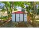 Backyard storage shed with a red roof surrounded by lush greenery at 1219 Michigan N Dr, Dunedin, FL 34698