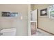 Compact half bathroom with a toilet and framed print; an adjacent room is visible at 1219 Michigan N Dr, Dunedin, FL 34698