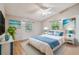 Bright bedroom with vaulted ceiling, ceiling fan, wood floors, and beach-themed artwork at 1219 Michigan N Dr, Dunedin, FL 34698