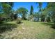 A wide shot of a grassy backyard showing the house and surrounding trees at 12302- Pittsfield Ave, Tampa, FL 33624