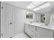 Well-lit bathroom featuring double sinks, a large mirror, and white cabinets at 13602 Frigate Ct # N201, Clearwater, FL 33762