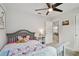 Bright bedroom featuring a ceiling fan, a cozy gray bed with colorful linens, and a peek into another room at 17652 Ramble On Way, Land O Lakes, FL 34638