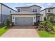 Charming two-story home with a brick driveway, a gray facade, and a well-manicured front lawn at 17652 Ramble On Way, Land O Lakes, FL 34638