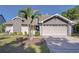 Charming home featuring a two-car garage, well-maintained lawn, and mature palm tree at 2015 Branch Tree Ln, Brandon, FL 33511