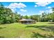 A screened pool and patio are featured in the backyard of this house with an expansive, grassy lot and wooded area at 24498 Casey Rd, Brooksville, FL 34601