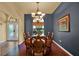 Dining room with wood table and chairs, chandelier, large window, and blue accent wall at 24498 Casey Rd, Brooksville, FL 34601