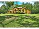 An elegant one-story home with beige stucco, an arched entryway, and mature landscaping on a sprawling lawn at 24498 Casey Rd, Brooksville, FL 34601