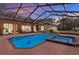 A bright blue swimming pool and hot tub is surrounded by a brick patio outside a home with patio furniture at sunset at 24498 Casey Rd, Brooksville, FL 34601
