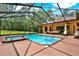 A bright blue swimming pool and hot tub is surrounded by a brick patio outside a home with patio furniture at 24498 Casey Rd, Brooksville, FL 34601