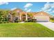 Inviting single-story home featuring a well-manicured lawn, a terracotta roof, and a covered entryway with classic architectural details at 30314 Fairway Dr, Wesley Chapel, FL 33543