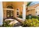 Elegant double front doors with decorative glass detailing and a covered porch with stately columns and lush landscaping at 30314 Fairway Dr, Wesley Chapel, FL 33543