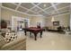 Open living space with a coffered ceiling, elegant chandelier, billiard table and access to the outdoor patio area at 30314 Fairway Dr, Wesley Chapel, FL 33543