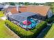 A screened-in pool with a jacuzzi, red umbrella and privacy hedge offers a secluded outdoor retreat at 30314 Fairway Dr, Wesley Chapel, FL 33543