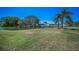 Spacious backyard featuring a tranquil lake view, mature trees, and lush green lawn at 3847 Lighthouse Way # 3847, New Port Richey, FL 34652