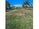 Expansive backyard with canal view, lush grass and mature palm trees under a clear blue sky at 3847 Lighthouse Way # 3847, New Port Richey, FL 34652