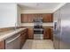 Well-equipped kitchen with stainless steel appliances, wooden cabinets, and granite countertops for meal preparation at 6343 Osprey Lake Circle, Riverview, FL 33578