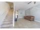 Bright living room with neutral tile flooring, staircase, and a comfy plaid sofa by the light-filled window at 6343 Osprey Lake Circle, Riverview, FL 33578