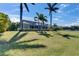 Expansive backyard featuring a pool, manicured lawn, palm trees, and screened enclosure at 718 Manns Harbor Dr, Apollo Beach, FL 33572