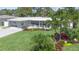 A single story home boasts a lush lawn, vibrant landscaping, covered porch, and a striking red front door for enhanced curb appeal at 7301 2Nd S Ave, St Petersburg, FL 33707