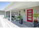 Charming front porch with brick floor, red door, stylish seating, and decorative plants creates a welcoming entrance at 7301 2Nd S Ave, St Petersburg, FL 33707