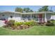 Beautiful home showcasing a well-maintained lawn and garden, complemented by a welcoming covered porch and a vibrant red front door at 7301 2Nd S Ave, St Petersburg, FL 33707