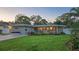 Charming single-story home with stone facade, manicured lawn, and colorful flower beds, complemented by a vibrant red front door at 7301 2Nd S Ave, St Petersburg, FL 33707