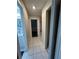 Hallway featuring tile flooring with closet, access to bathroom and stairs at 7601 Como Dr, New Port Richey, FL 34655