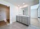 Bathroom featuring double sinks, gray cabinets, and modern tile flooring, connecting to walk-in closet at 7782 Sail Clover Ln, Zephyrhills, FL 33540