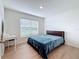 Well-lit bedroom with hardwood floors, a large window, and a desk area at 7782 Sail Clover Ln, Zephyrhills, FL 33540