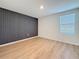 Modern bedroom with accent wall, light wood-look floors, and a bright window, offering style and comfort at 7782 Sail Clover Ln, Zephyrhills, FL 33540