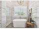 Bathroom with freestanding tub, decorative tiled walls, and a window with shutters at 813 Manns Harbor Dr, Apollo Beach, FL 33572