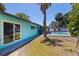 A vibrant teal home exterior featuring a swimming pool, lush landscaping, and ample outdoor space at 8401 Stillbrook Ave, Tampa, FL 33615