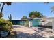 Charming home with a covered carport, vibrant turquoise exterior, and well-maintained landscaping at 8401 Stillbrook Ave, Tampa, FL 33615
