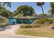Charming turquoise home featuring lush landscaping, solar panels, and a welcoming front patio at 8401 Stillbrook Ave, Tampa, FL 33615