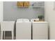 Bright laundry room features a sink, washer and dryer, open shelving, and neutral walls at 9652 Runaway Breeze Dr, Land O Lakes, FL 34637