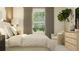Bright main bedroom features a large window, neutral decor, hardwood floors, and a stylish accent chair at 9652 Runaway Breeze Dr, Land O Lakes, FL 34637